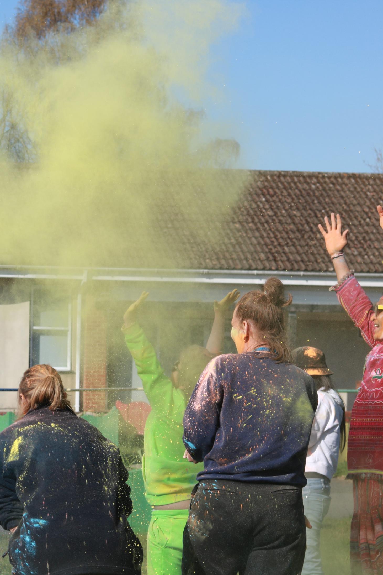 group of people with colour powder flying up in the air