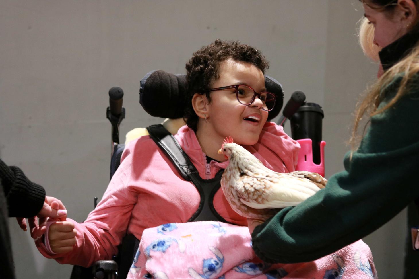 Keira smiling looking at a chicken being held by a member of staff