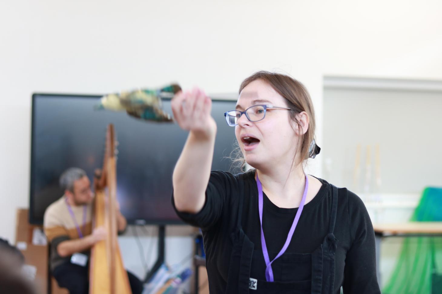 Lady with bird puppet, harpist playing in the background