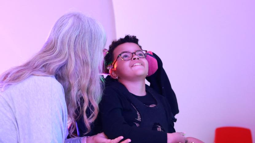 child using sensory board assisted by adult