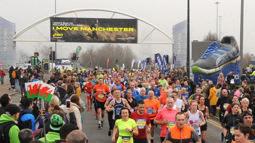 colourful runners running under large banner and oversized trainer on a grey day
